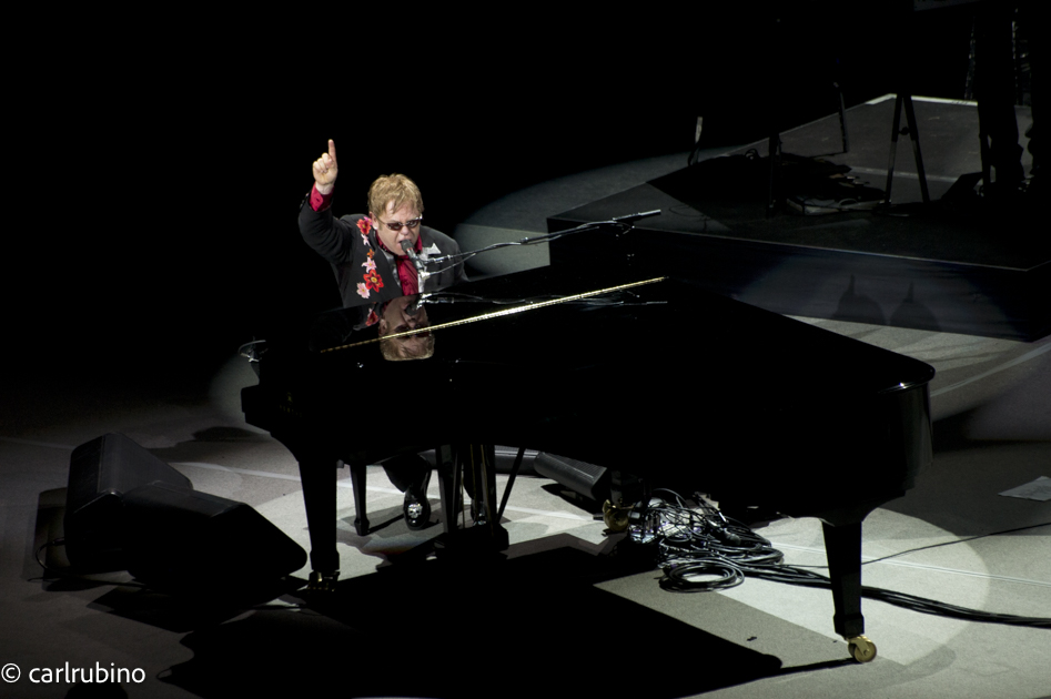 Sir Elton, at Saratoga Performing Arts Center, shot from the balcony.  This one took some special efforts.  I shoved a 200mm telephoto lens down my pants leg at the gate, figuring they'd never touch it, and walked in with a small mirrorless "tourist-looking" camera.  When the lights went down I popped the big lens on and got this shot, catching the reflection of Elton's face on the top of the piano.